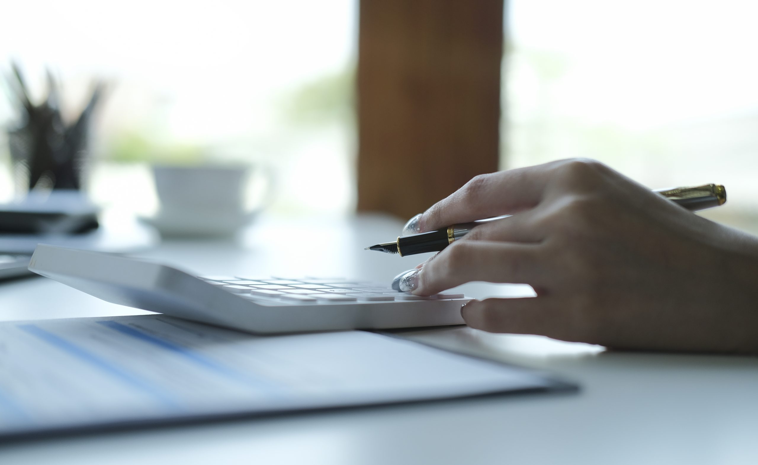 accountant using a calculator and analyzing finance chart at office desk.